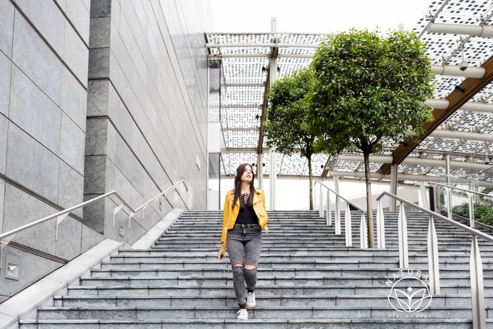 woman walking down long flight of stairs with one hand in pocket